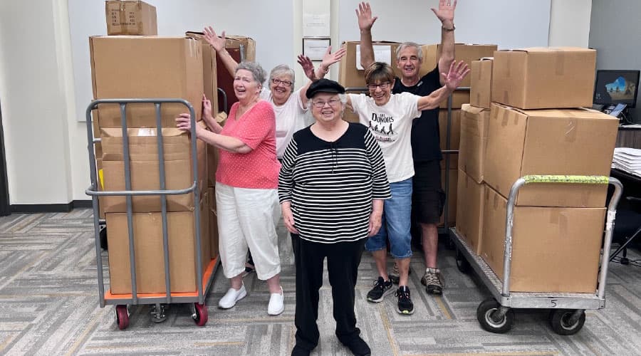Smiling volunteers with two carts filled with boxes.
